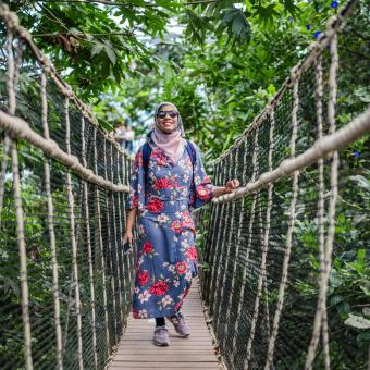 Woman walking across bridge in the Rainforest Biome